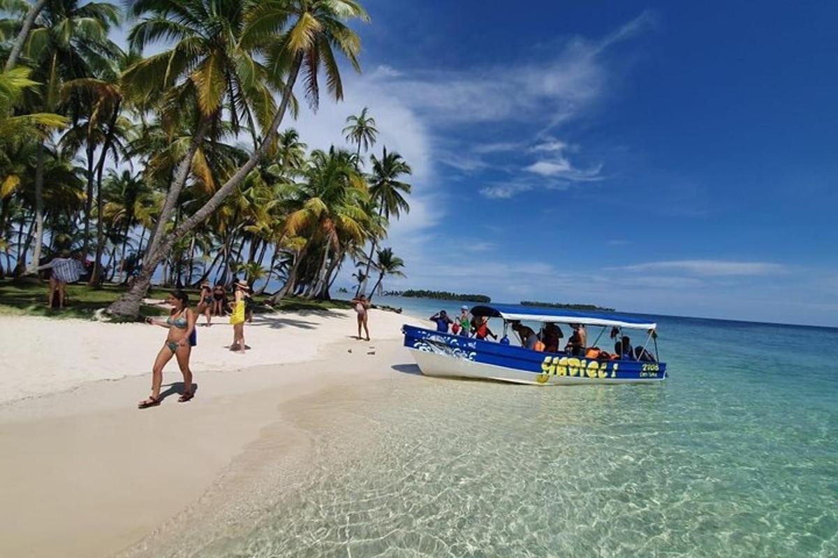 một chiếc thuyền màu xanh trên bãi biển với mọi người trên đó