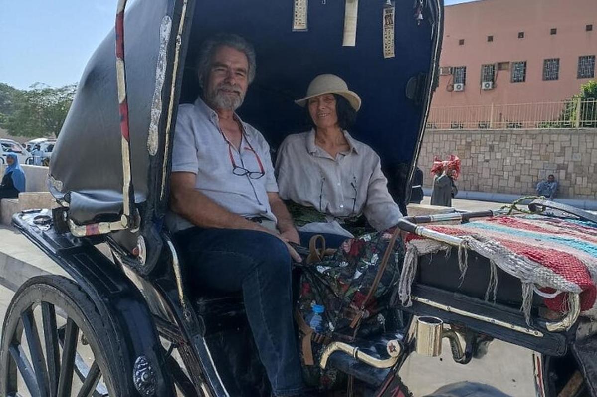 un uomo e una donna seduti in una carrozza trainata da cavalli