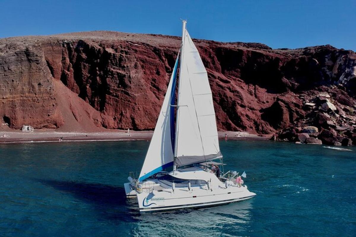 a white sailboat in the water near a mountain