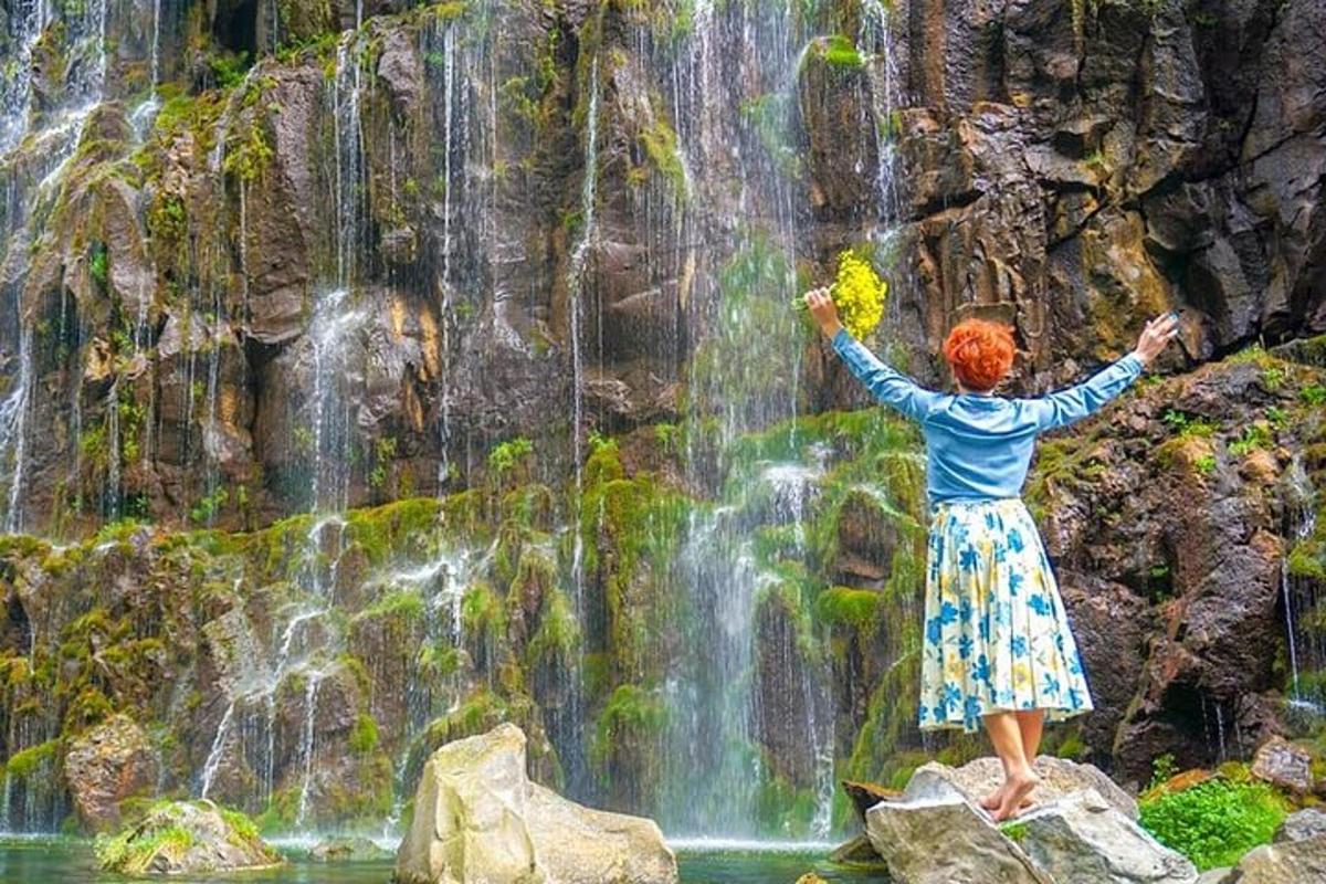 امرأة تقف على صخرة أمام شلال