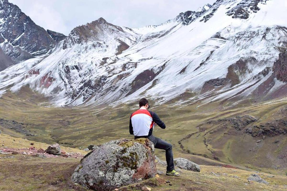 Un hombre parado sobre una roca mirando una montaña
