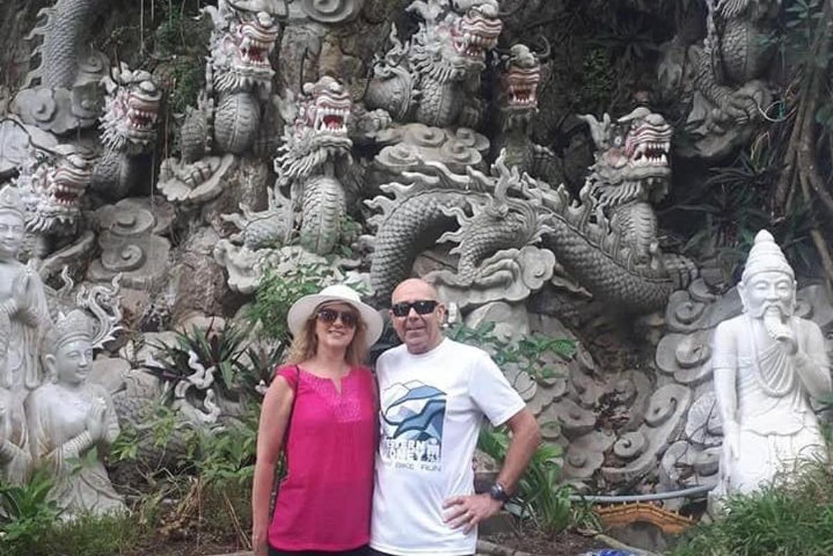 un homme et une femme debout devant un mur de pierre