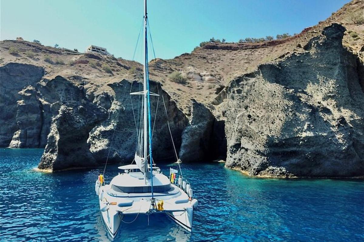 μια άσπρη βάρκα στο νερό δίπλα σε μερικούς βράχους