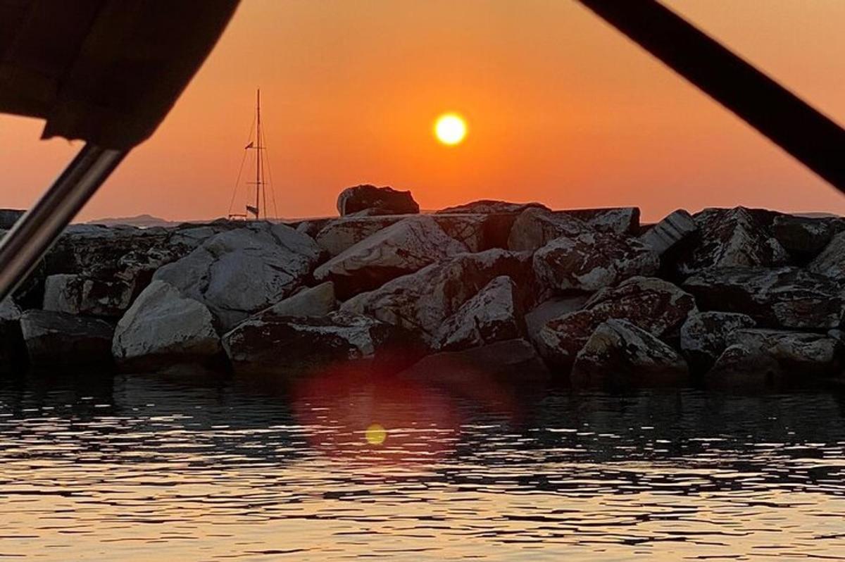 a sunset over a group of rocks in the water