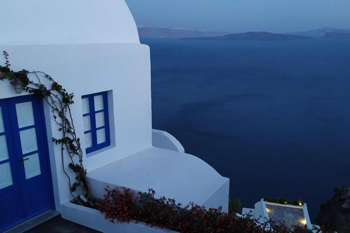 Un edificio blanco con una puerta azul y el agua.