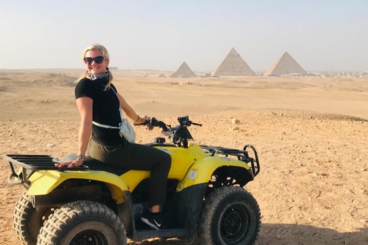 nainen istuu mönkijällä pyramidien edessä