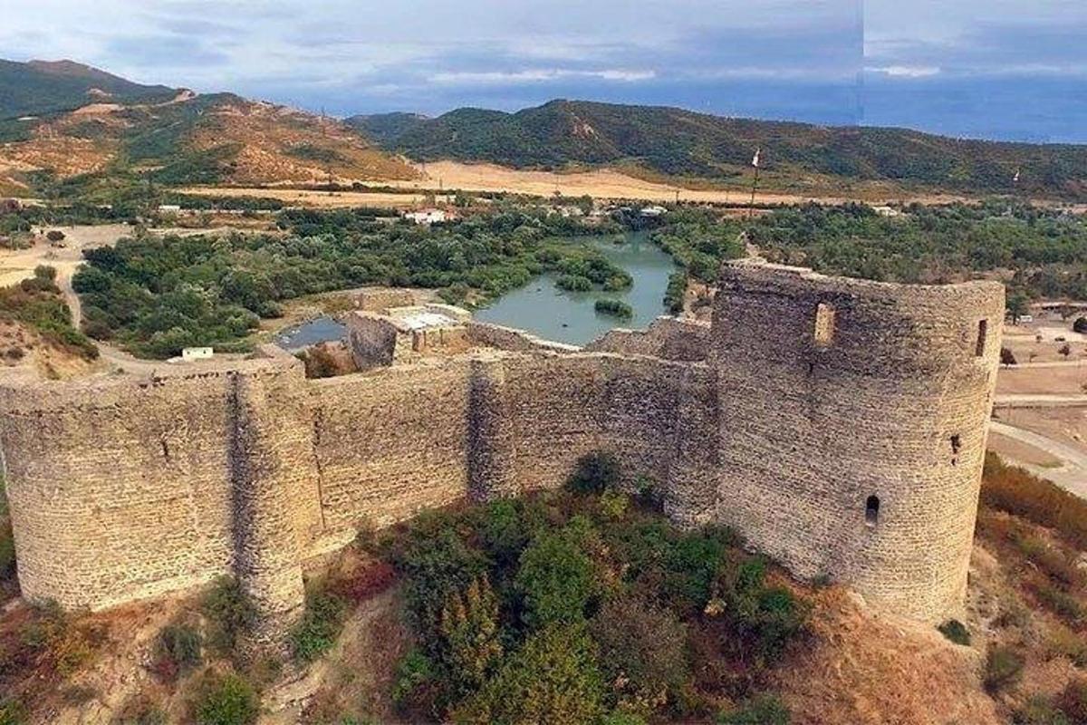 un castel vechi cu un lac în față