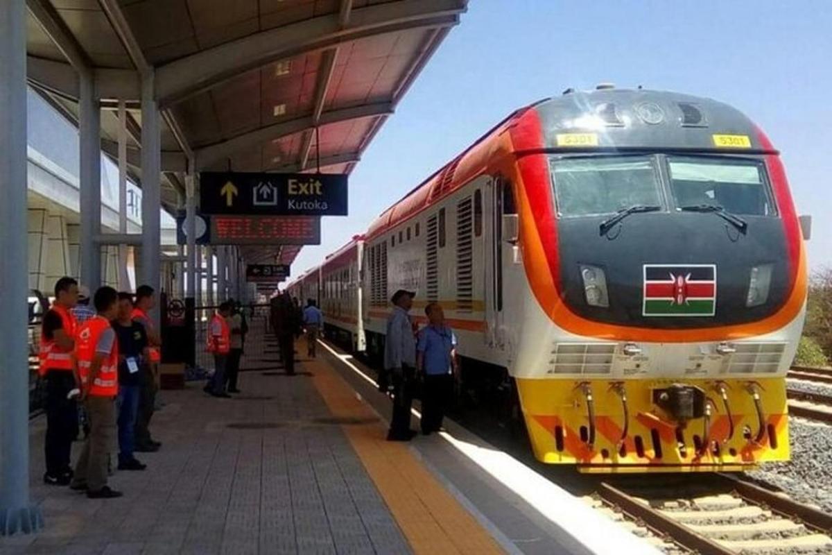 isang tren sa isang istasyon ng tren na may mga taong naghihintay sa plataporma