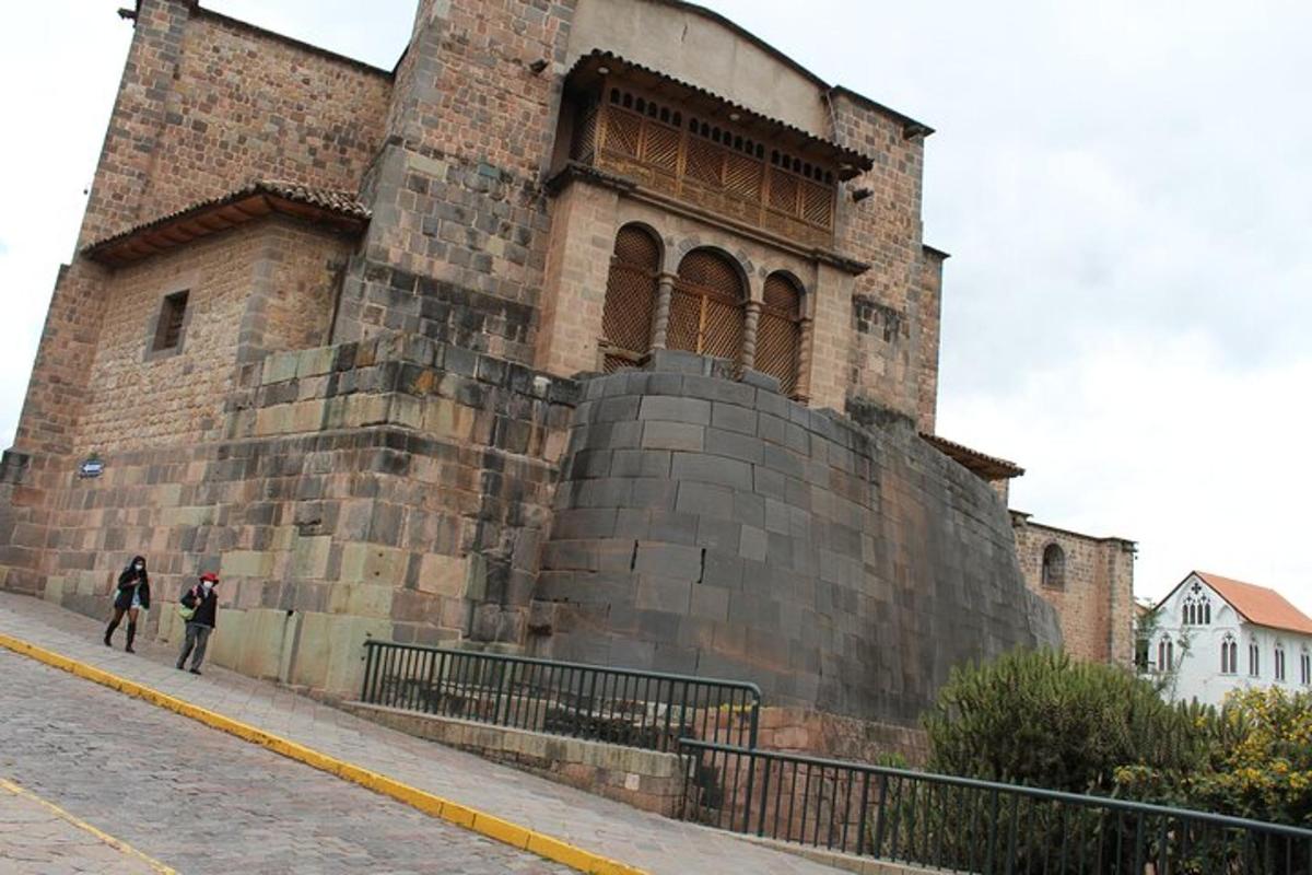 duas pessoas caminhando em frente a um grande edifício de tijolos