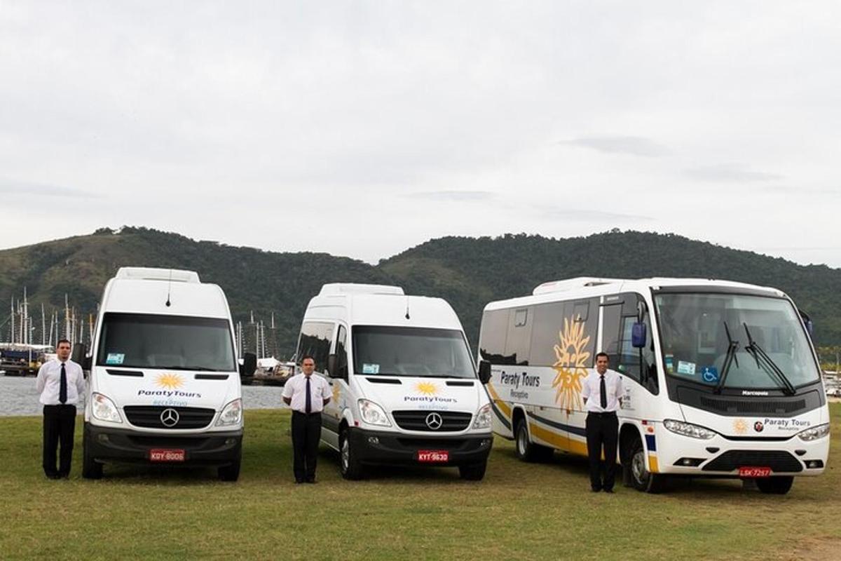 Un grupo de hombres de pie entre dos autobuses blancos.