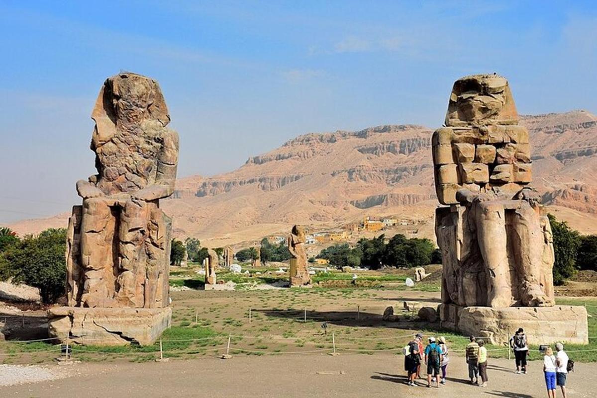un gruppo di persone che camminano vicino a due grandi statue di pietra