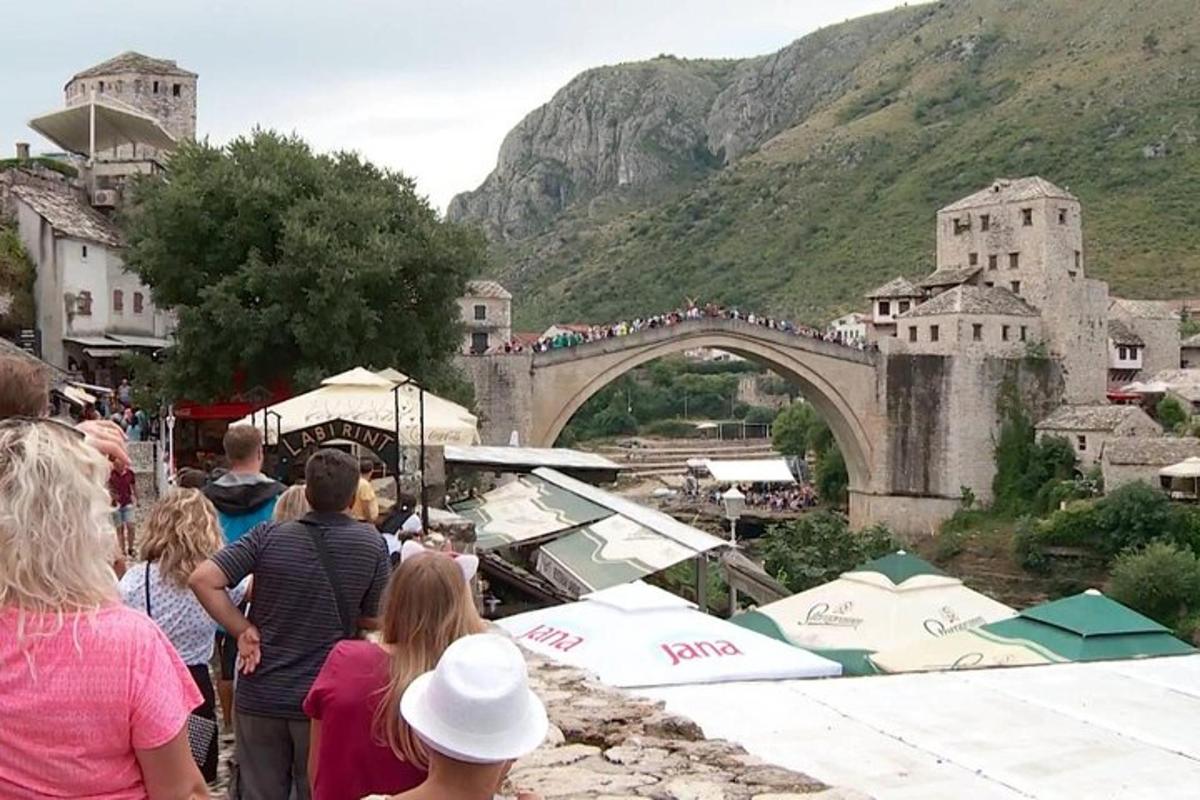 Un grupo de personas de pie cerca de un puente con una multitud.