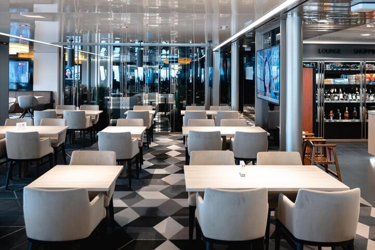 um restaurante com mesas e cadeiras brancas e piso xadrez