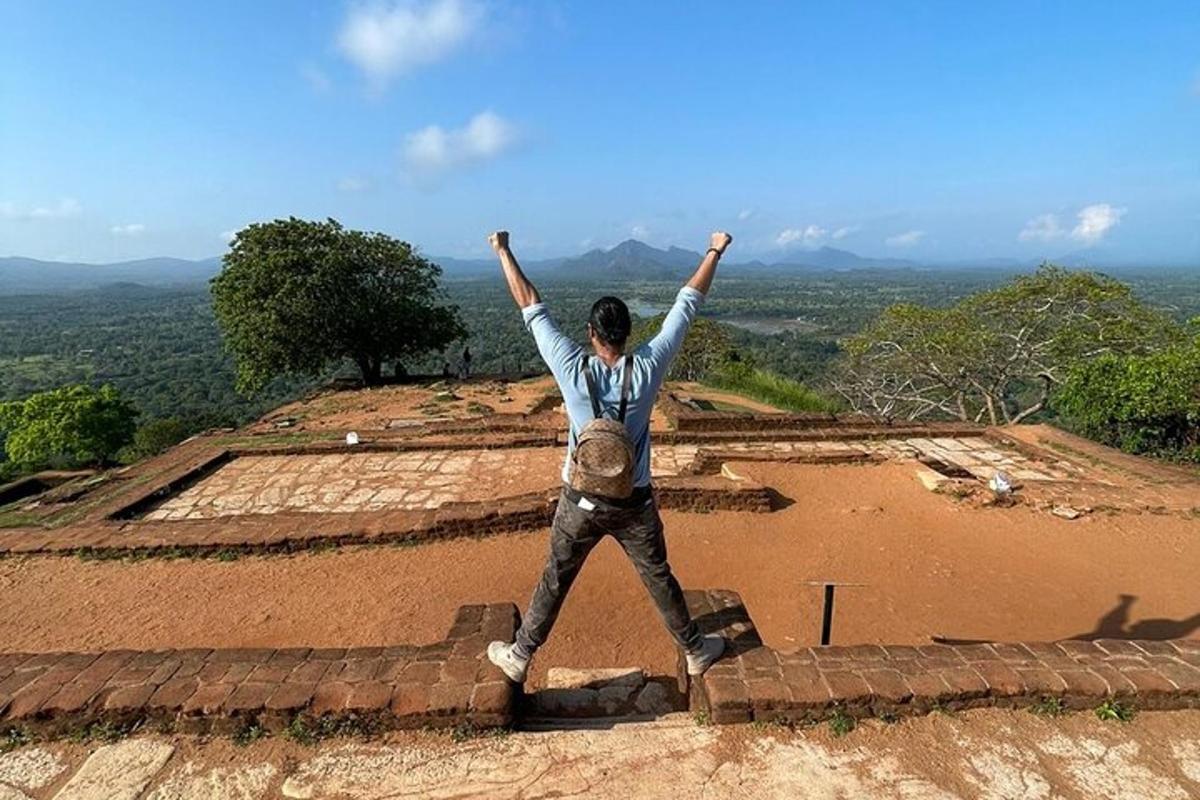 seorang lelaki berdiri di atas bukit dengan tangan di udara