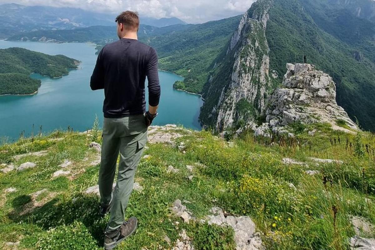 moški, ki stoji na vrhu gore s pogledom na jezero