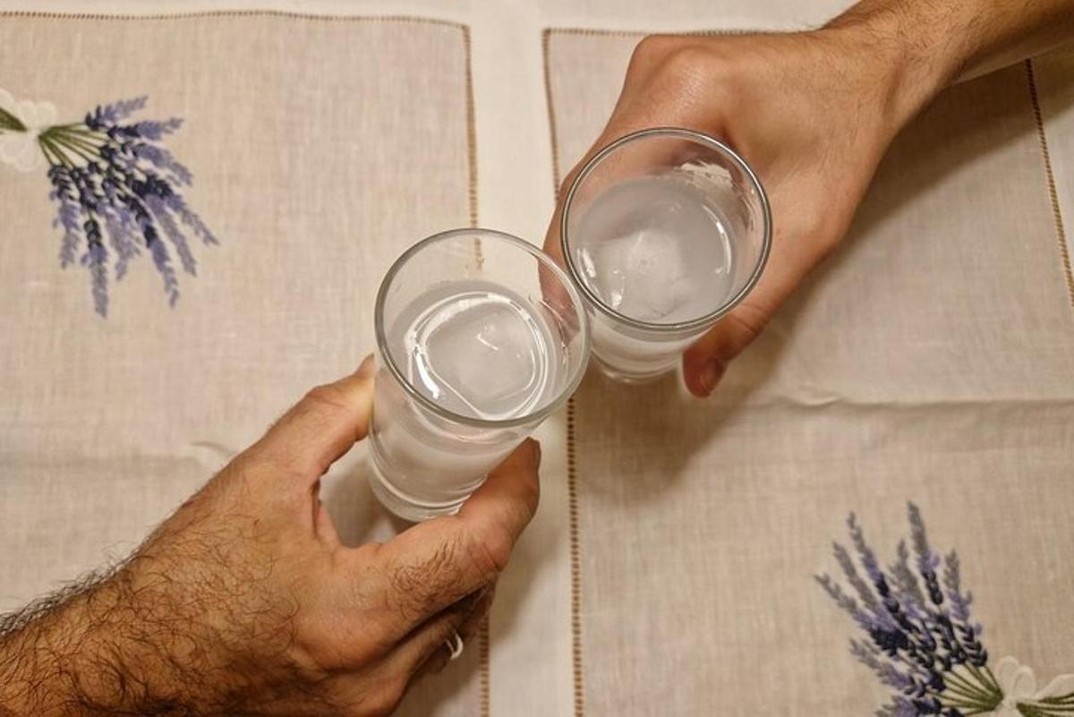 two hands holding two glasses of water on a table
