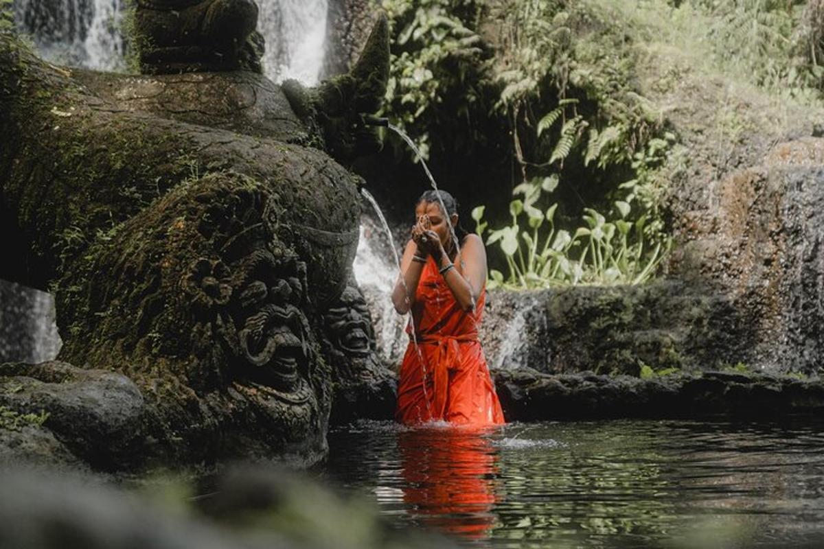 una dona dempeus a l'aigua davant d'una cascada