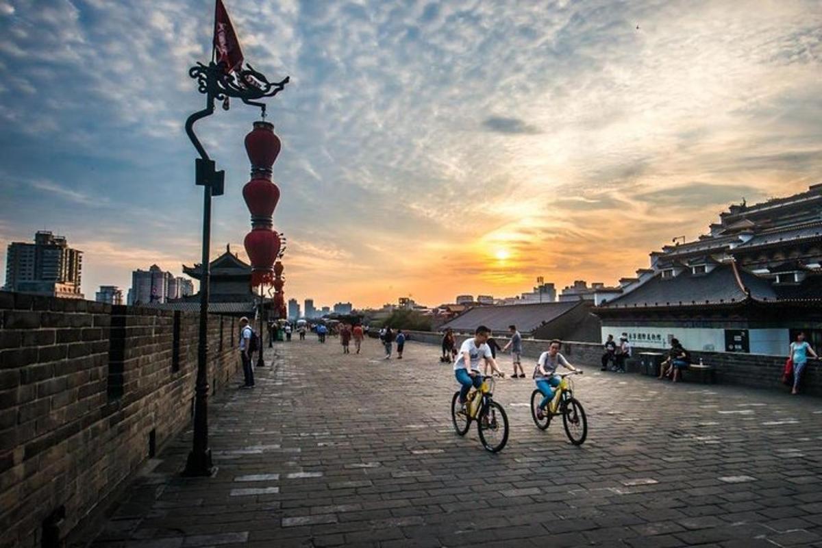 a group of people riding bikes down a street at sunset