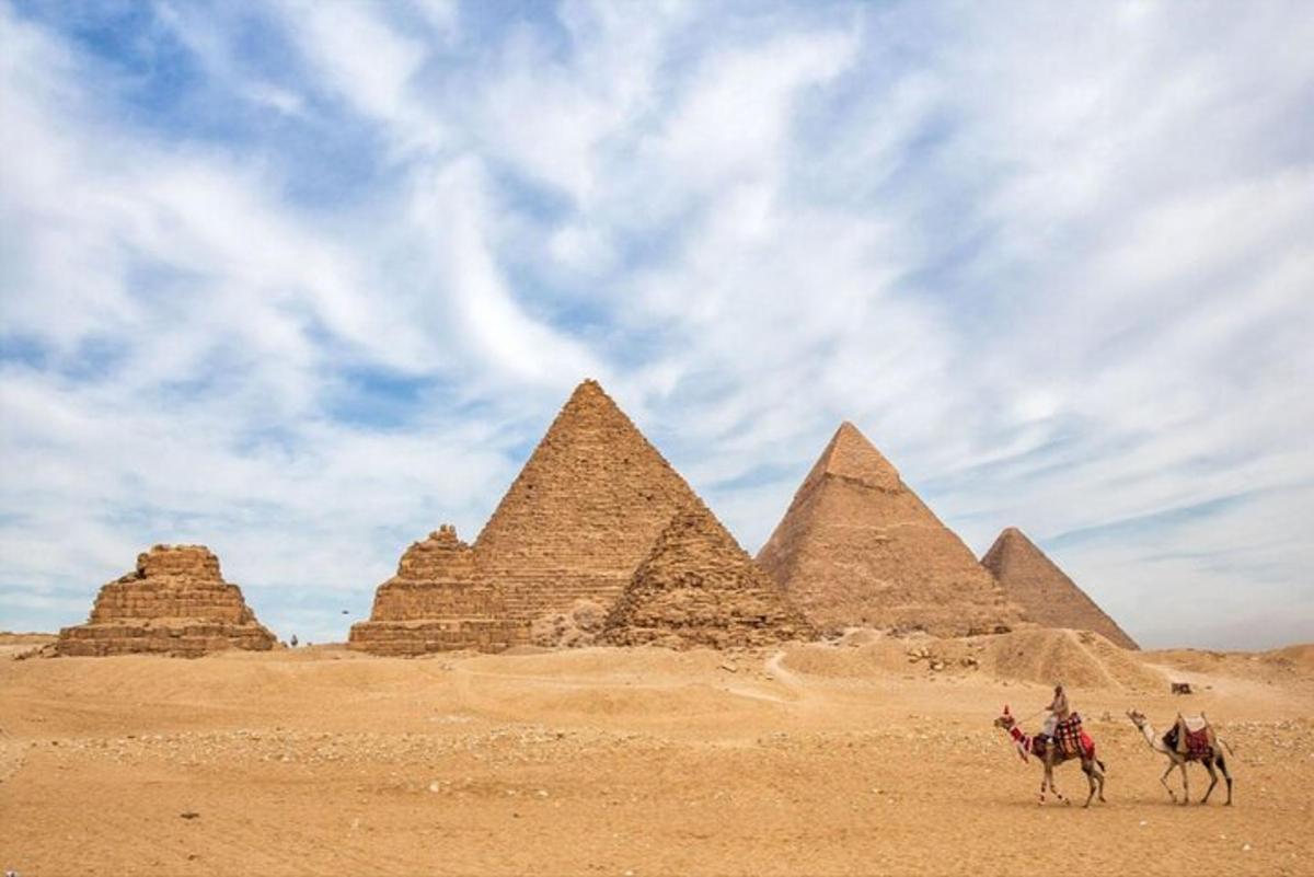 مجموعة من الناس يركبون الجمال أمام الأهرامات