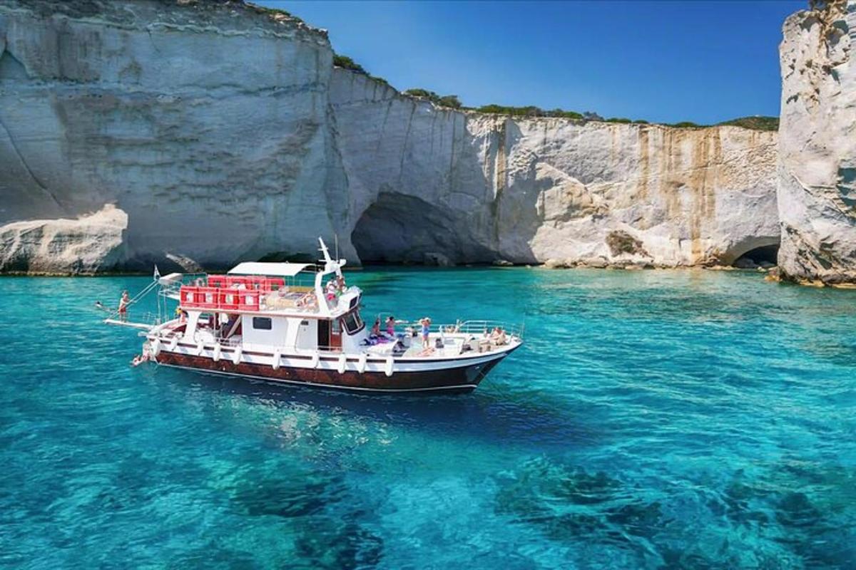 a boat in the water next to a cliff