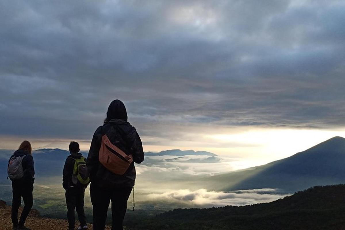 three people standing on top of a mountain