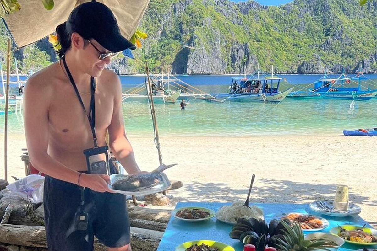 a man holding a plate of food on a beach