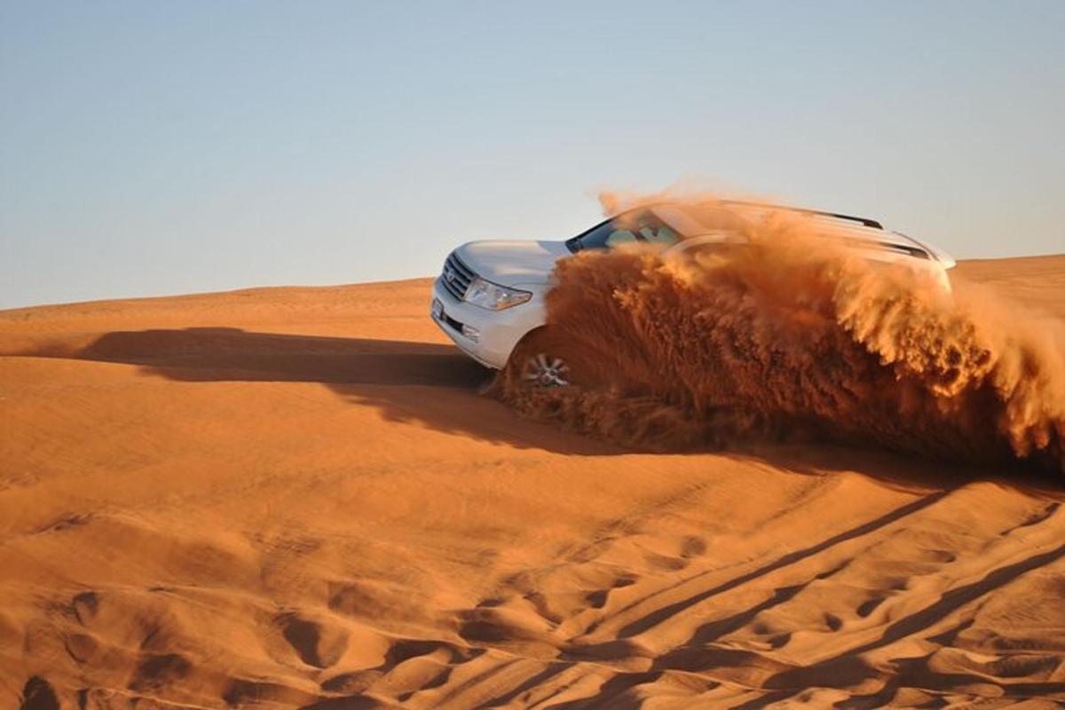 Un coche circulando por la arena del desierto.