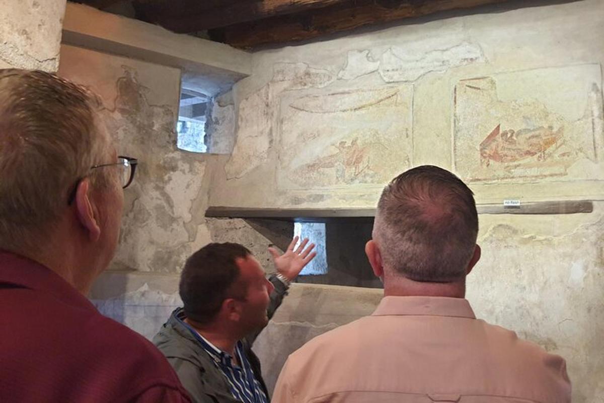 Un grupo de hombres mirando una pintura en una pared.