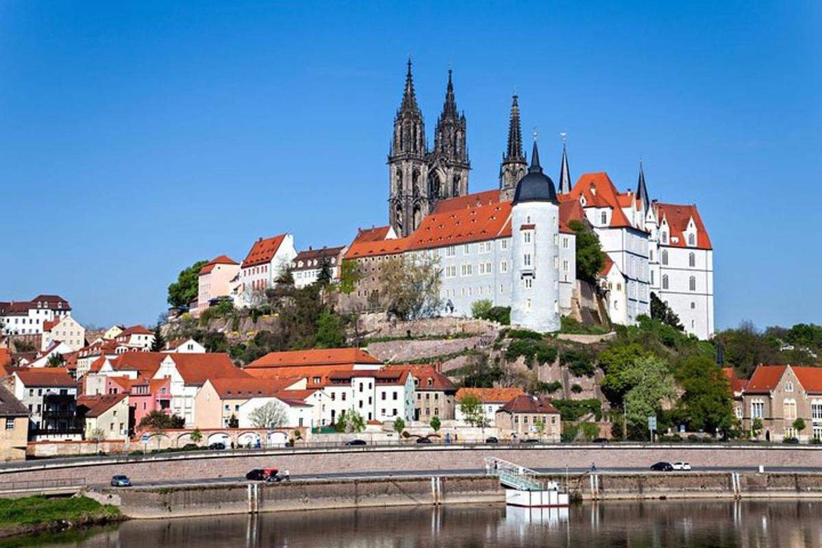 uma cidade no alto de uma colina com um castelo e um rio