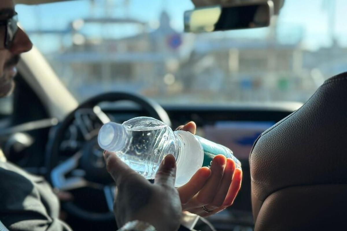 una persona sentada en un coche sosteniendo una botella de plástico