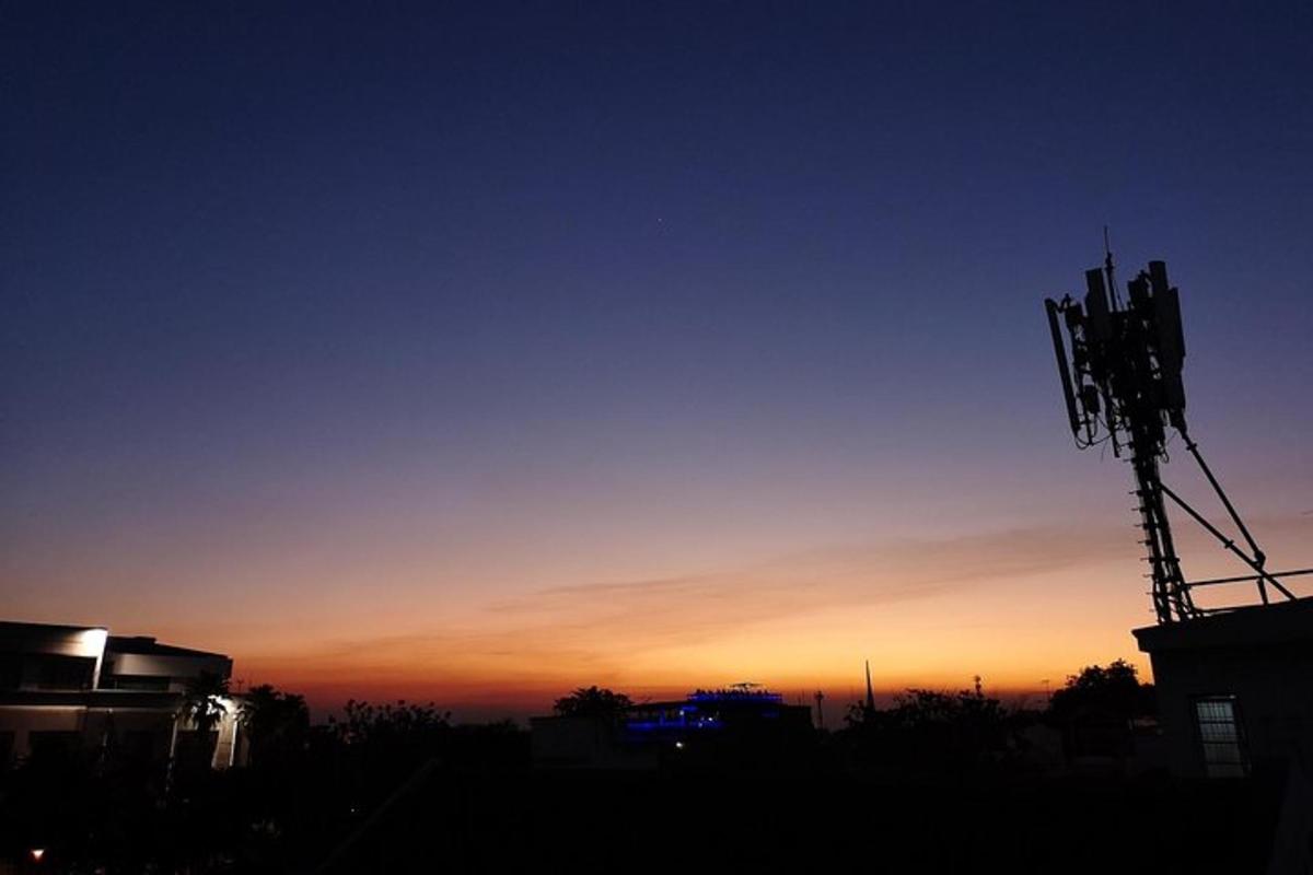 matahari terbenam dengan siluet antena telefon bimbit