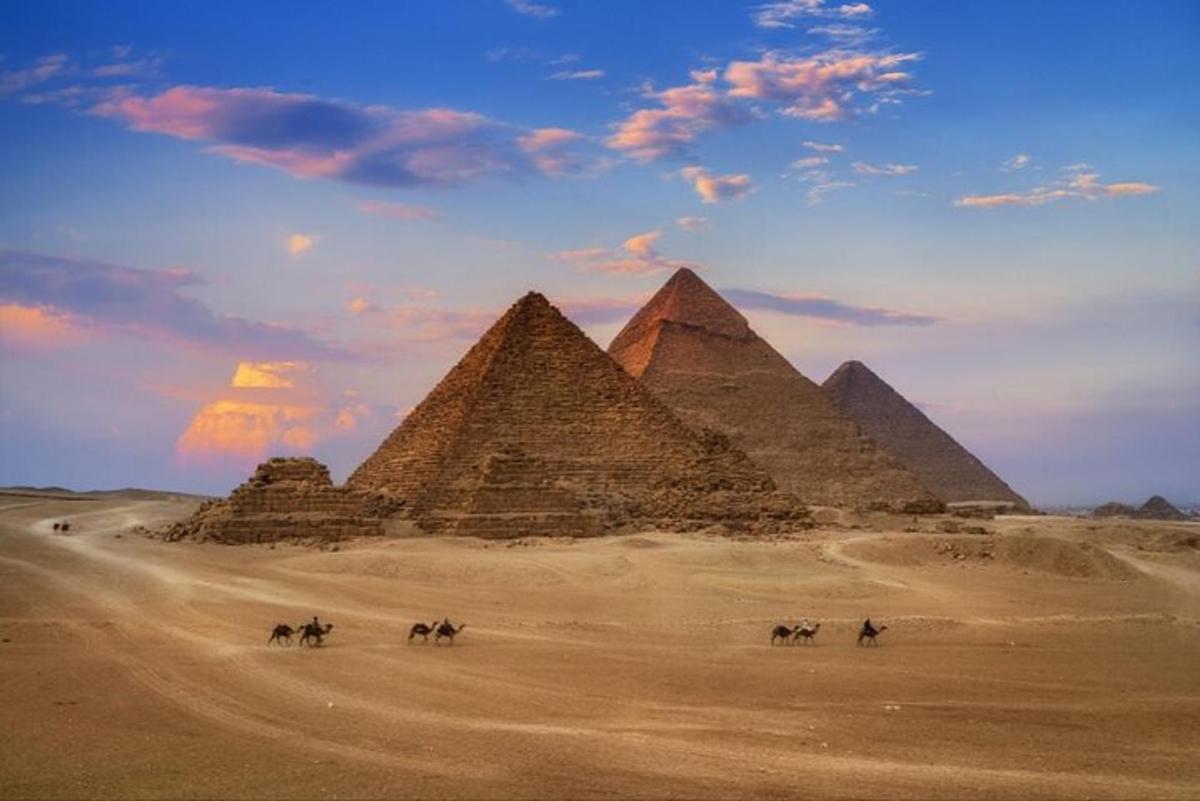 skupina ľudí jazdiacich na koňoch pred pyramídami