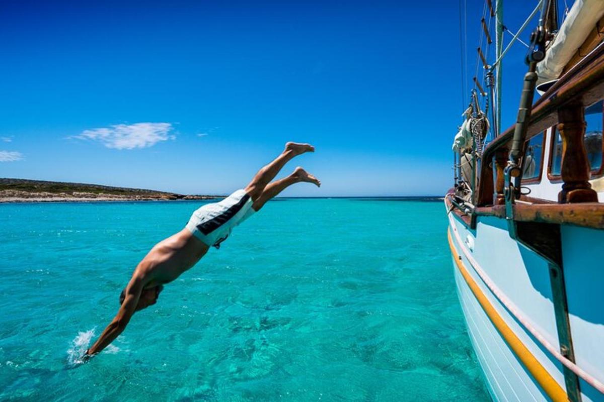 Un hombre se zambulle en el agua desde un bote.
