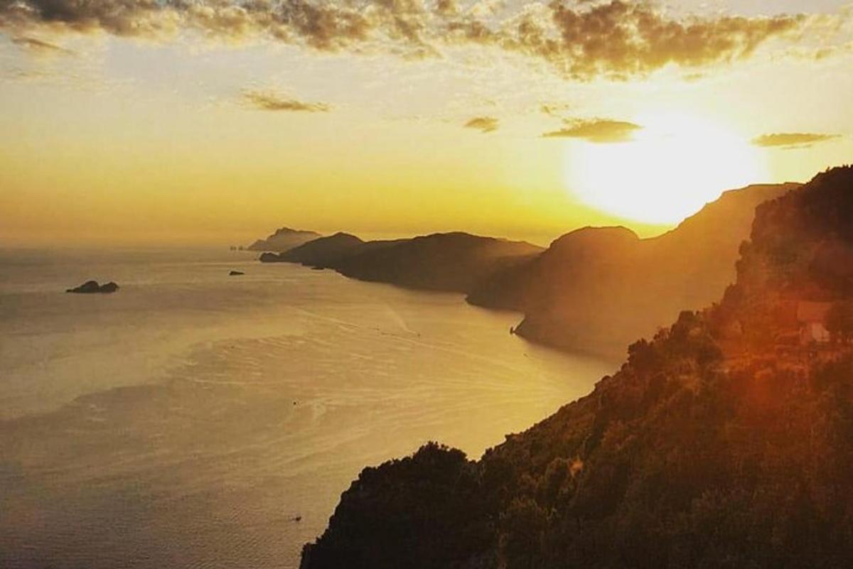 ein Sonnenuntergang über dem Meer mit einem Berg