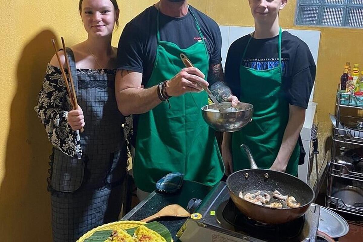 kolm inimest köögis wok-pannil toitu valmistamas