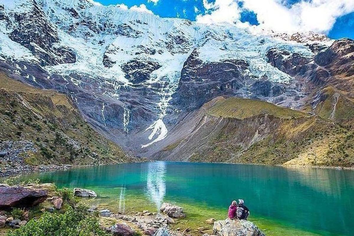 due persone sedute su una roccia vicino a un lago di montagna