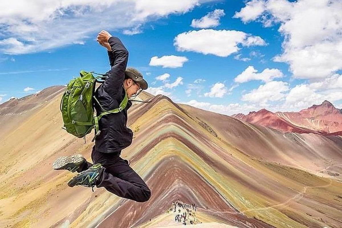 Un hombre con una mochila verde saltando en el aire