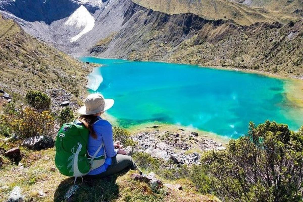 una donna seduta su una montagna che guarda un lago blu