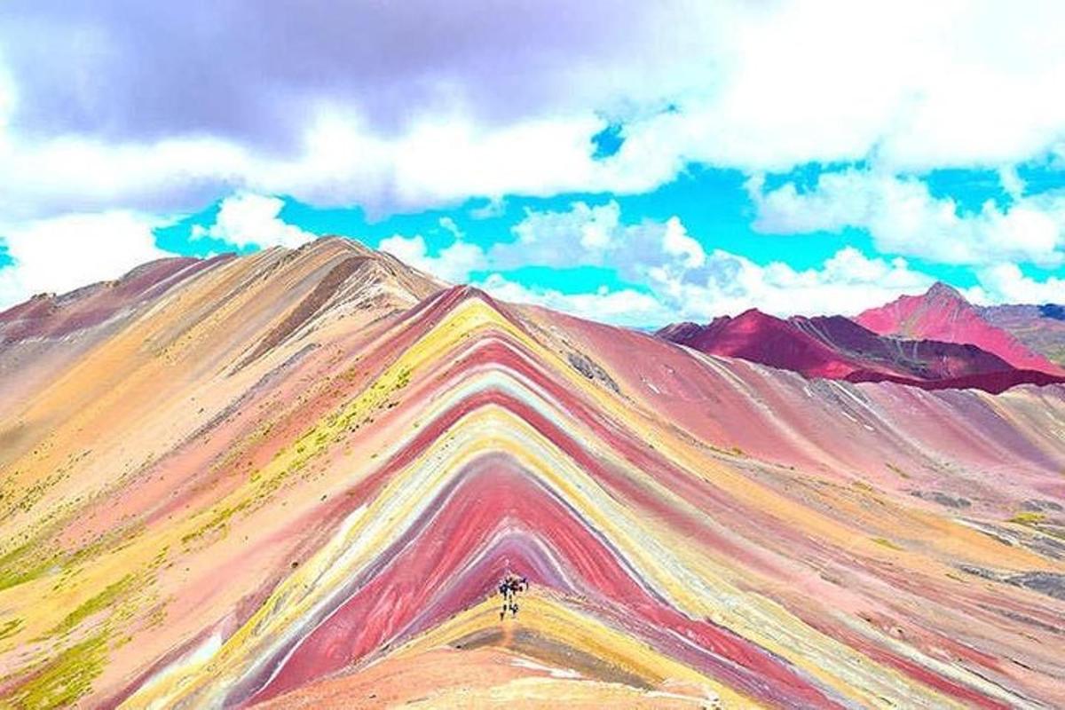 a rainbow colored mountain with a person standing on top