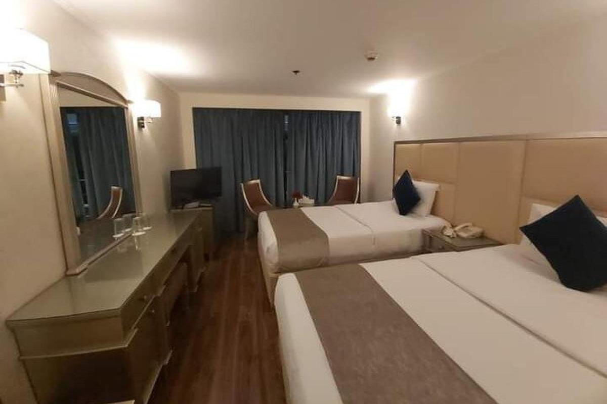 um quarto de hotel com duas camas e uma televisão