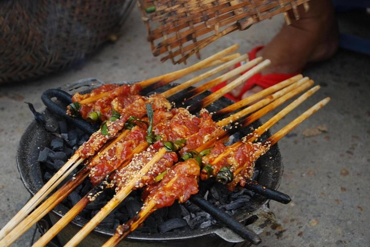 a bunch of food on a grill with chopsticks