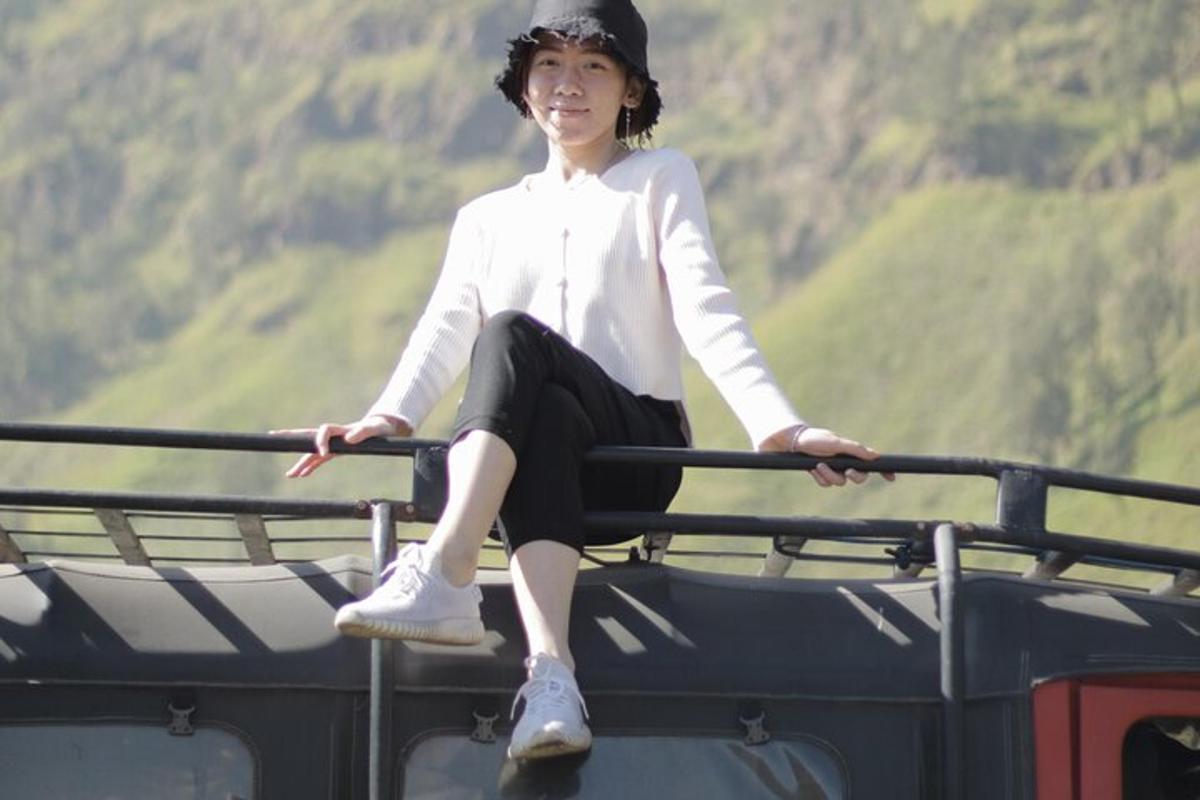 a young woman sitting on the top of a vehicle