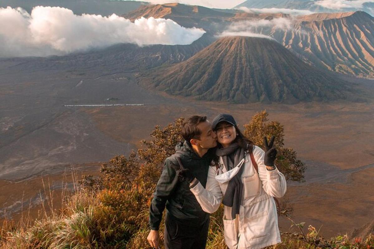 a man and woman kissing on top of a mountain