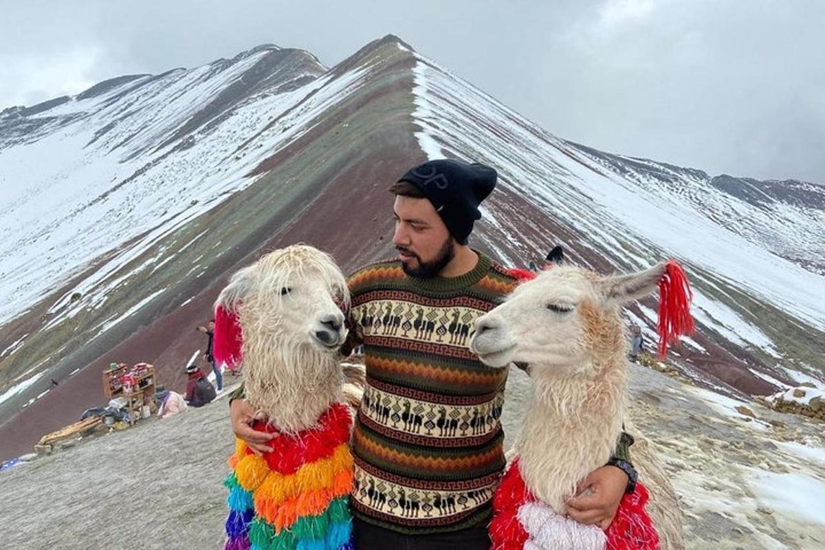 un homme tenant deux chèvres blanches devant une montagne
