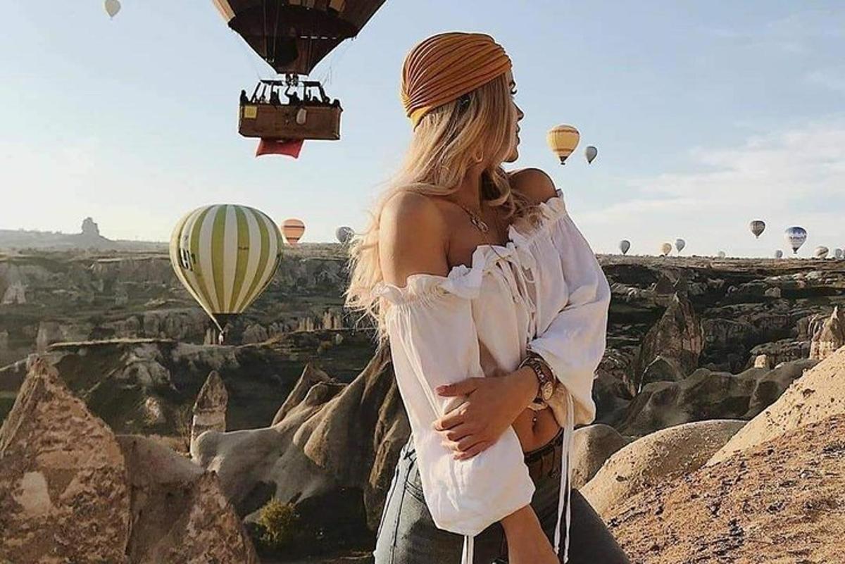 una donna in piedi su una scogliera con mongolfiere