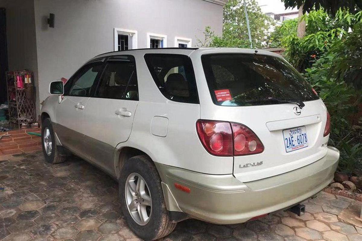um pequeno carro branco estacionado em frente a uma casa