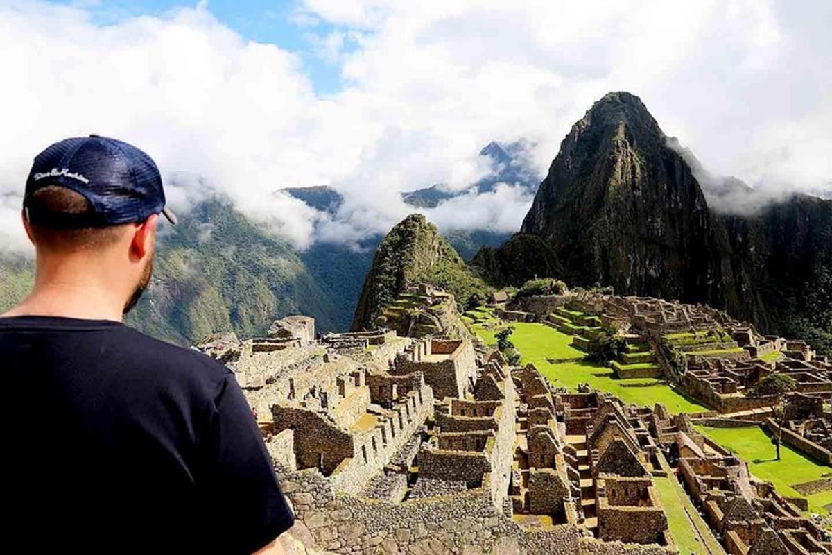 a man standing on top of a mountain looking at a ruins