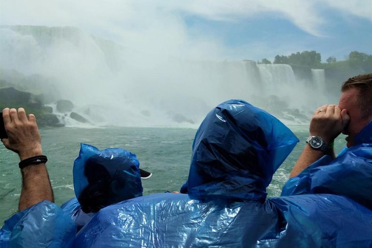 two people in blue raincoats looking at a waterfall