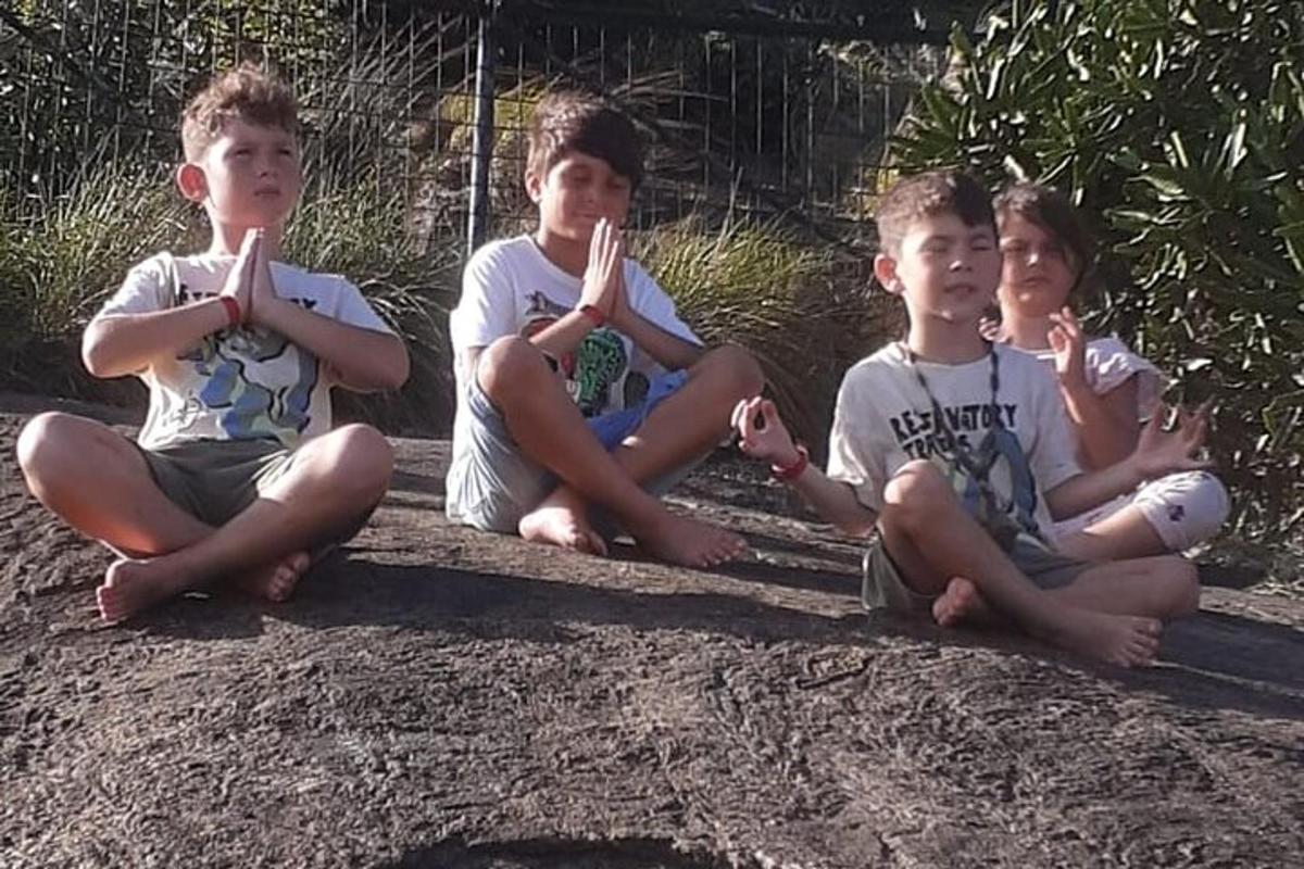 três meninos sentados no chão com os dedos na boca