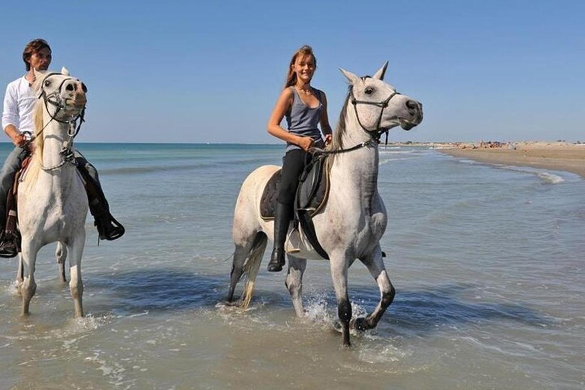 un uomo e una donna a cavallo sulla spiaggia